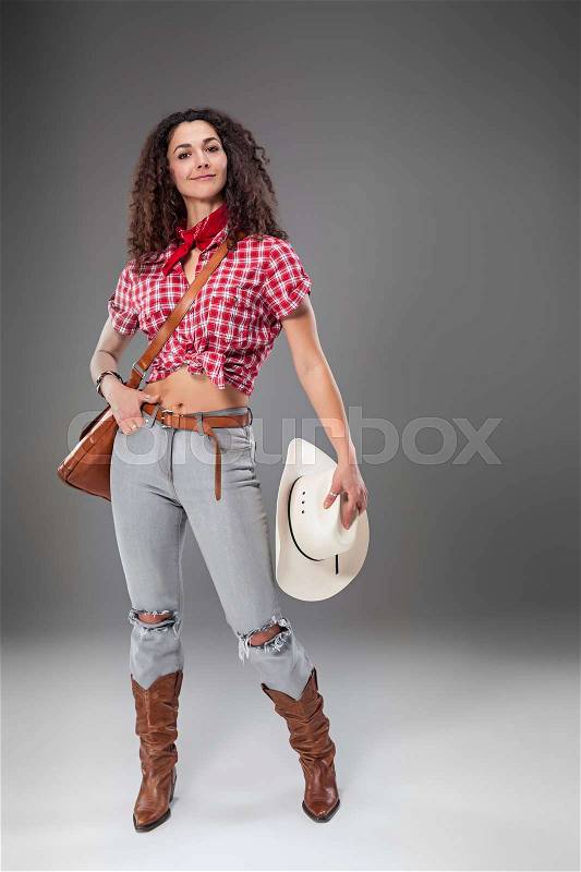 The cowgirl fashion woman over a gray studio background, stock photo