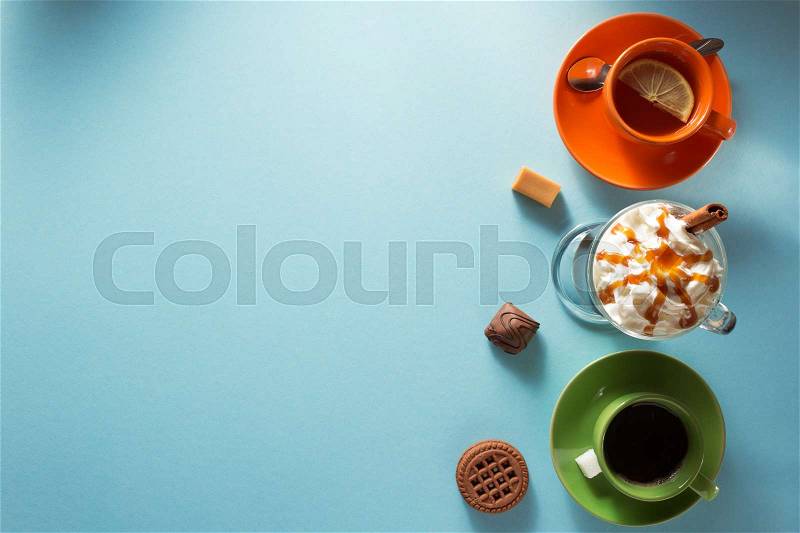 Cup of ice cream coffee, tea and cacao at blue paper background, stock photo