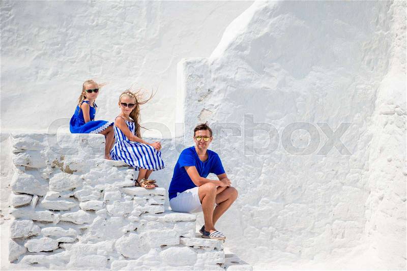 Family of three on the stairs of Paraportiani church on Mykonos Island, in Greece, stock photo