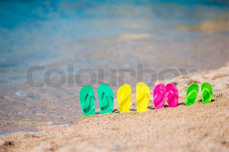 Family colorful flip flops on beach in front of the sea, stock photo