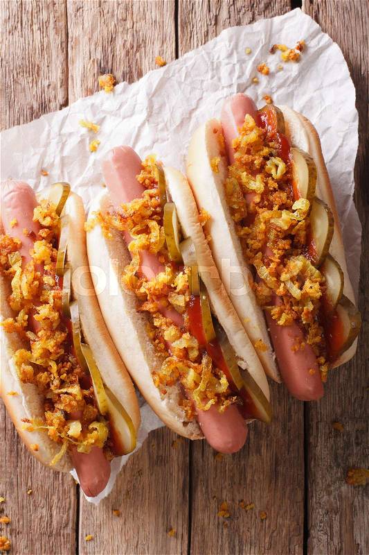 Danish food: hot dogs with crispy onions and pickled cucumbers close-up on the table. vertical view from above , stock photo