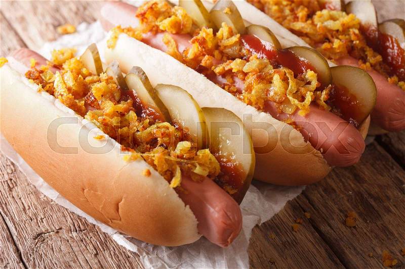 Danish fast food hot dogs with crispy onions, ketchup and pickled cucumbers close-up on the table. horizontal , stock photo