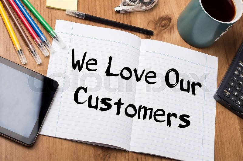 We Love Our Customers - Note Pad With Text On Wooden Table - with office tools, stock photo