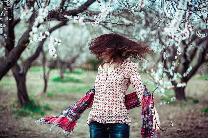 Girl hair develops on the background of blooming trees, positive, stock photo