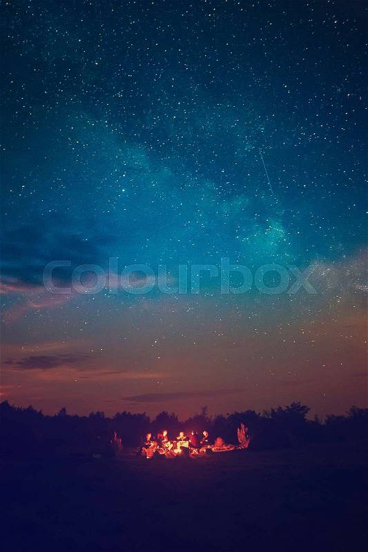 Camping fire under the amazing blue starry sky with a lot of shining stars and clouds. Travel recreational outdoor activity concept, stock photo