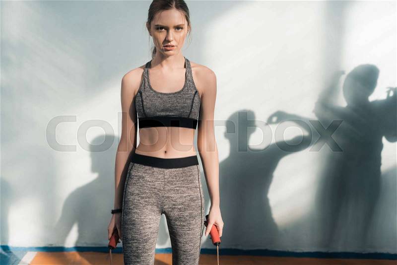 Sporty young woman with skipping rope looking at camera, stock photo