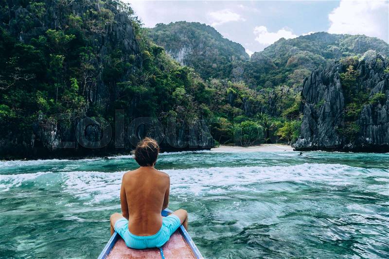 Back view of the man relaxing on the boat and looking at the island. Travelling tour in Asia: El Nido, Palawan, Philippines, stock photo