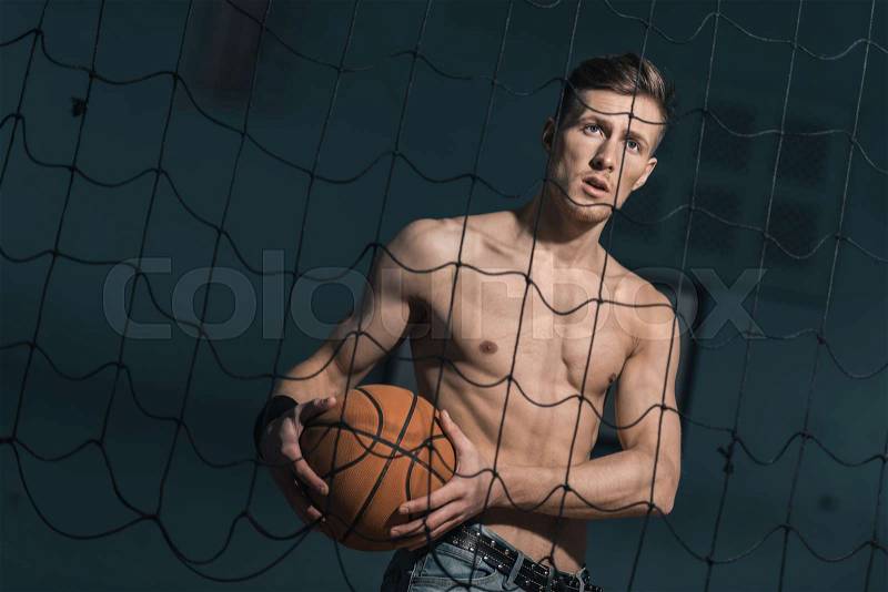 Portrait of emotional sporty man holding basketball ball, stock photo