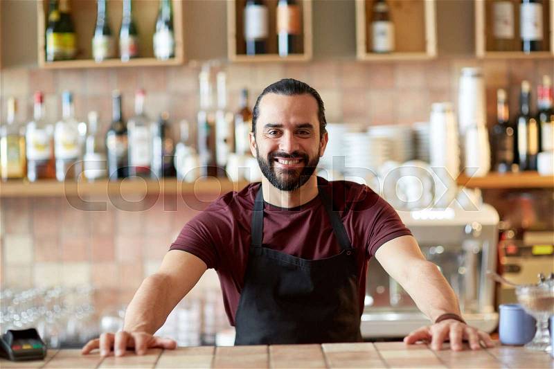Small business, people and service concept - happy man or waiter in apron at bar or coffee shop, stock photo