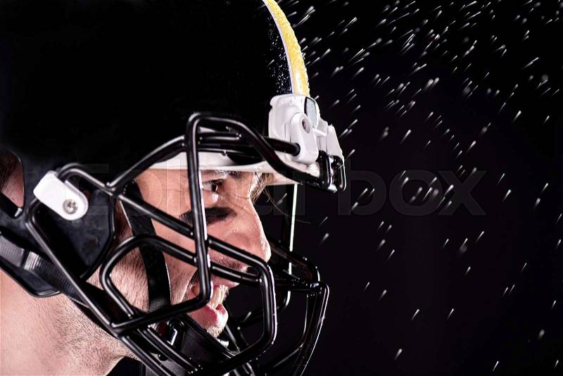 Close-up side view of angry man american football player in helmet on black, stock photo