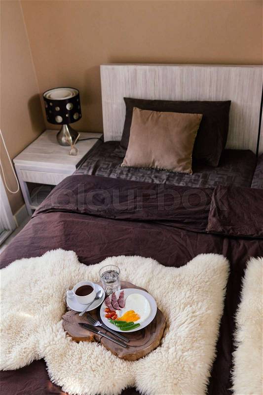Breakfast on a wooden tray in hotel bedroom, brown linen, modern interior, stock photo