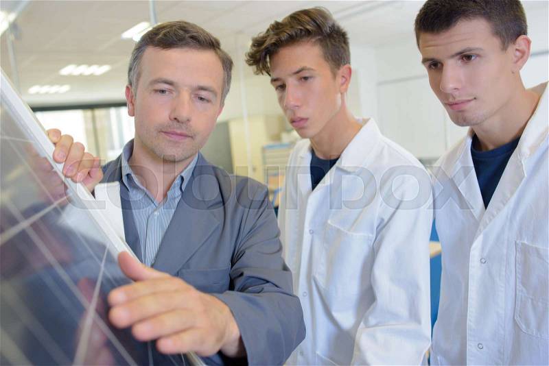 Man with students touching solar panel, stock photo
