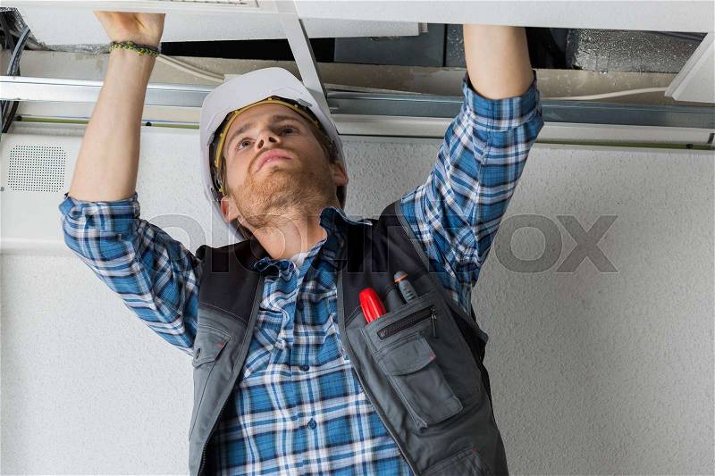 Electrical worker wiring in ceiling, stock photo