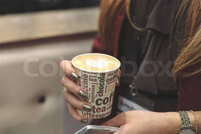 Business woman holds in her hand cup of cappuccino with heart during a business meeting (reduced tone), stock photo