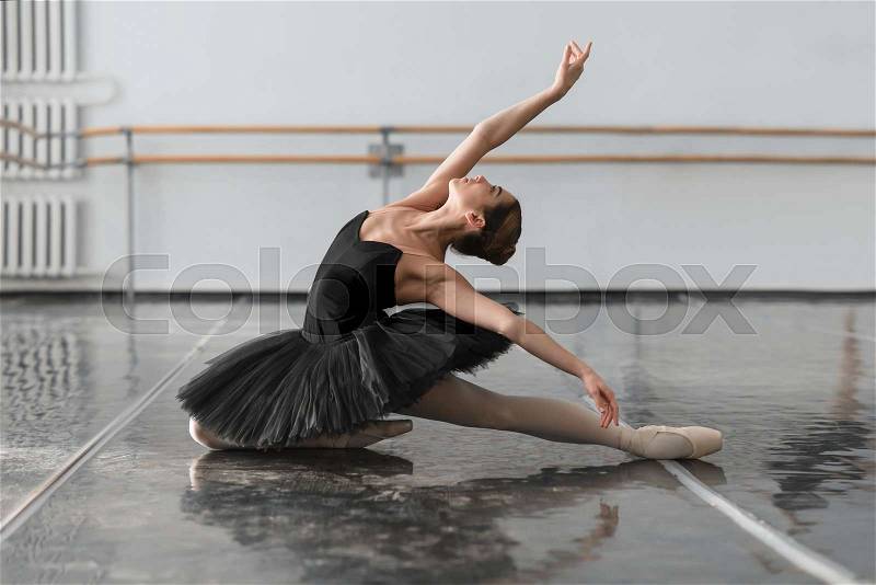 Beautiful ballerina sit on the twine in class. Legs stretching exercise, stock photo