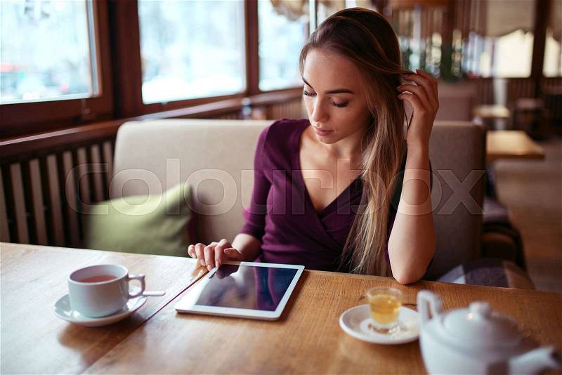 Beautiful woman with tablet pc using internet in restaurant. Girl with modern gadget using 4g in restaurant, stock photo