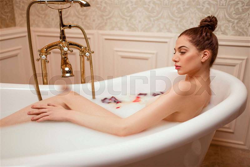 Beautiful woman in bath with rose petals and foam, stock photo