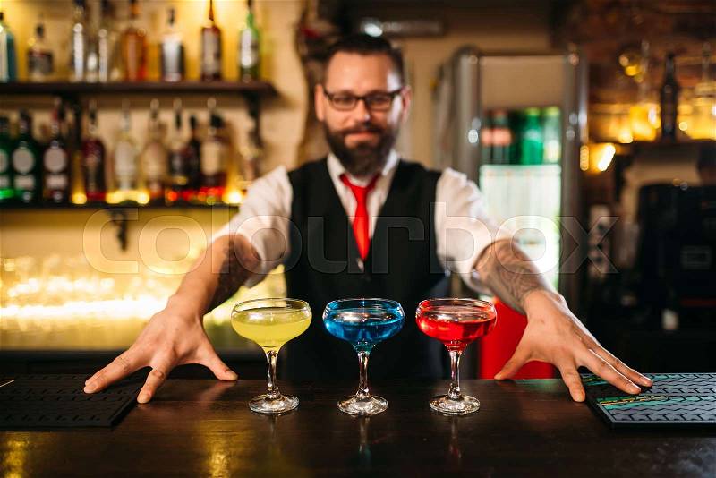 Bartender behind bar counter show alcohol coctails in restaurant, stock photo