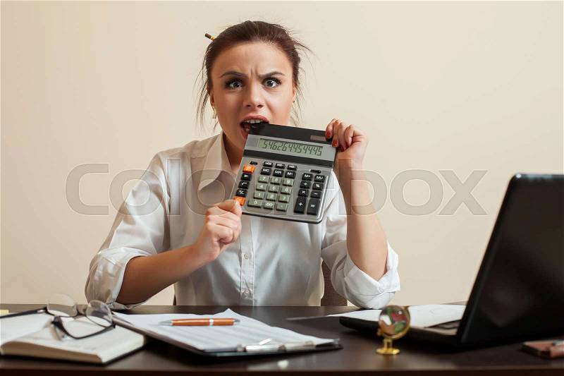 Afraid female bookkeper gnaws calculator. Scared woman bookkeeper concept, stock photo