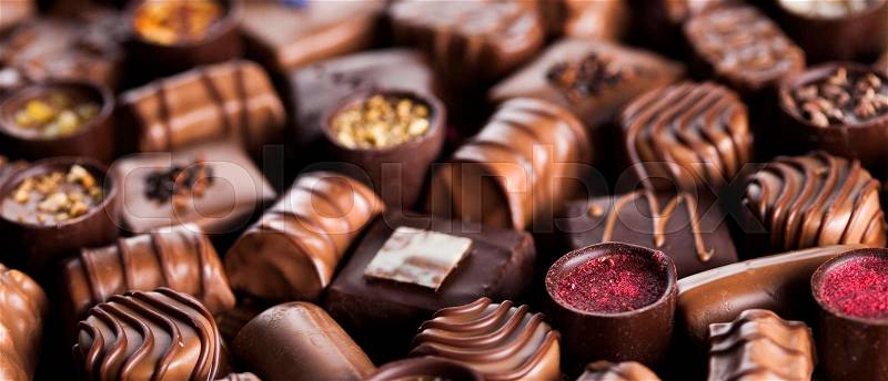 Chocolate bars and pralines on wooden background, stock photo