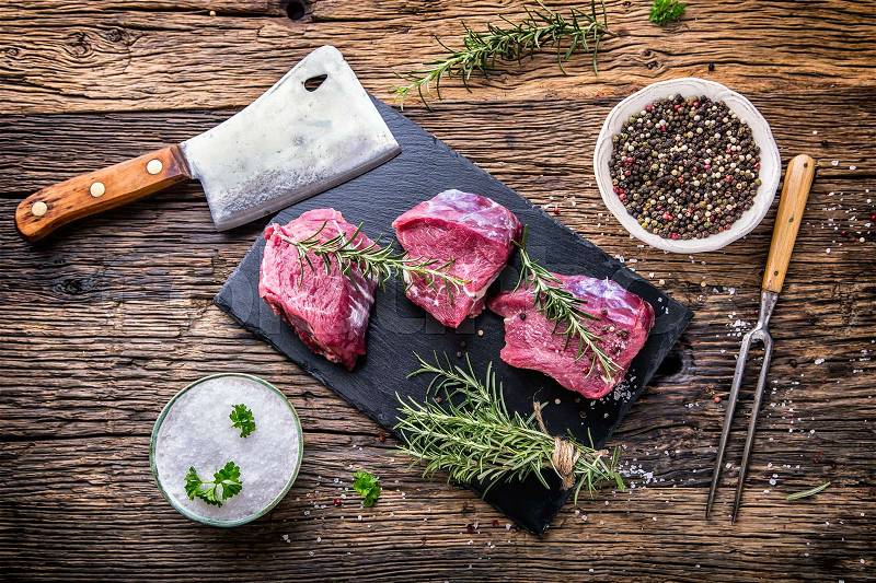Raw beef meat. Raw beef tenderloin steak on a cutting board with rosemary pepper salt in other positions, stock photo