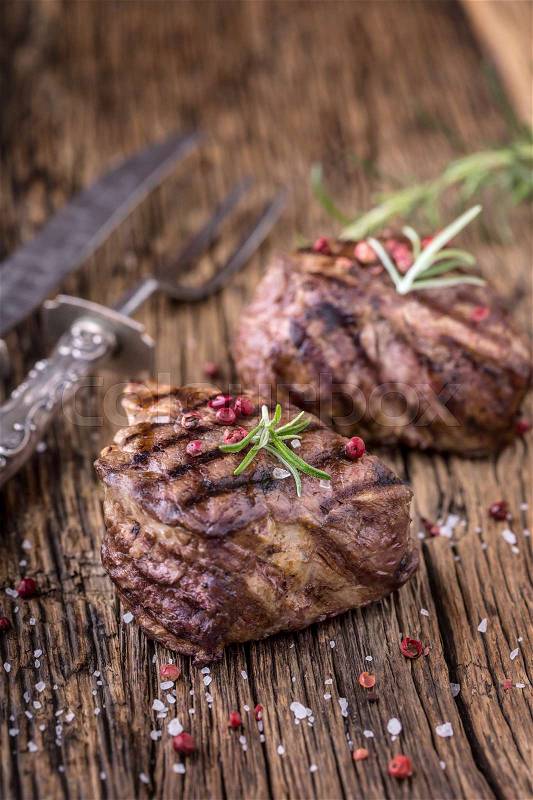 Grilled beef steak with rosemary, salt and pepper on old cutting board. Beef tenderloin steak, stock photo