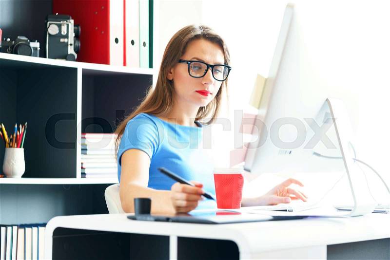Graphic designer drawing something on graphic tablet at the home office, stock photo