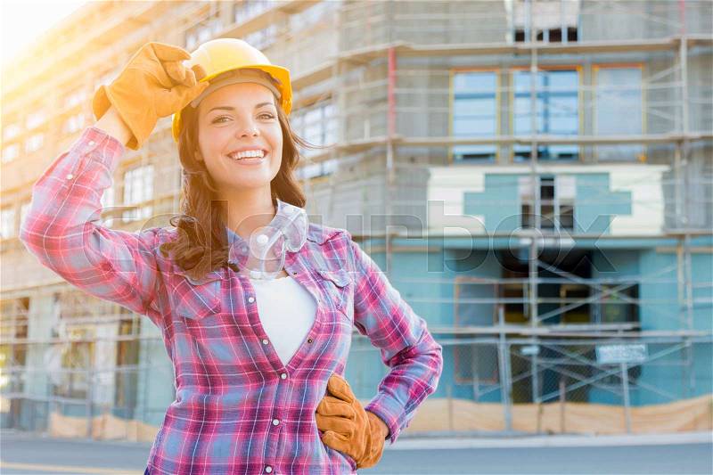 Portrait of Young Female Construction Worker Wearing Gloves, Hard Hat and Protective Goggles at Construction Site, stock photo