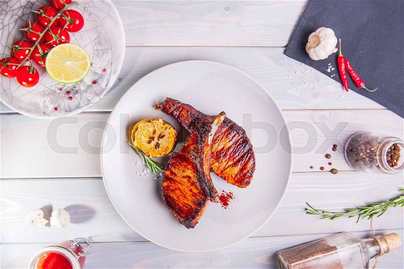 Top view Grilled pork ribs with grilled vegetables on the white plate on the wooden background with details. Selective focus, stock photo