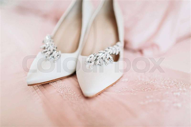 Bride\'s shoes for the wedding day on pink bed sheet. Selective focus, stock photo