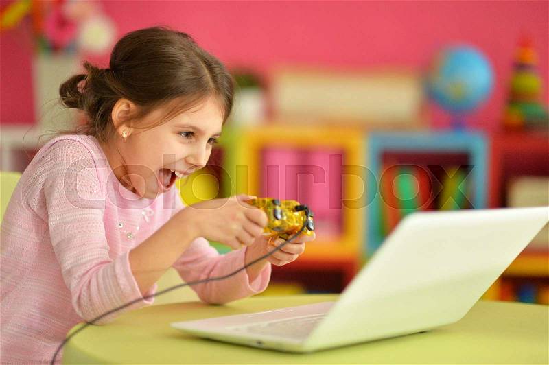 Little girl is playing a computer game, stock photo