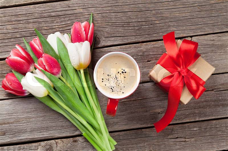 Colorful tulips, gift box and red coffee cup on wooden table. Top view, stock photo