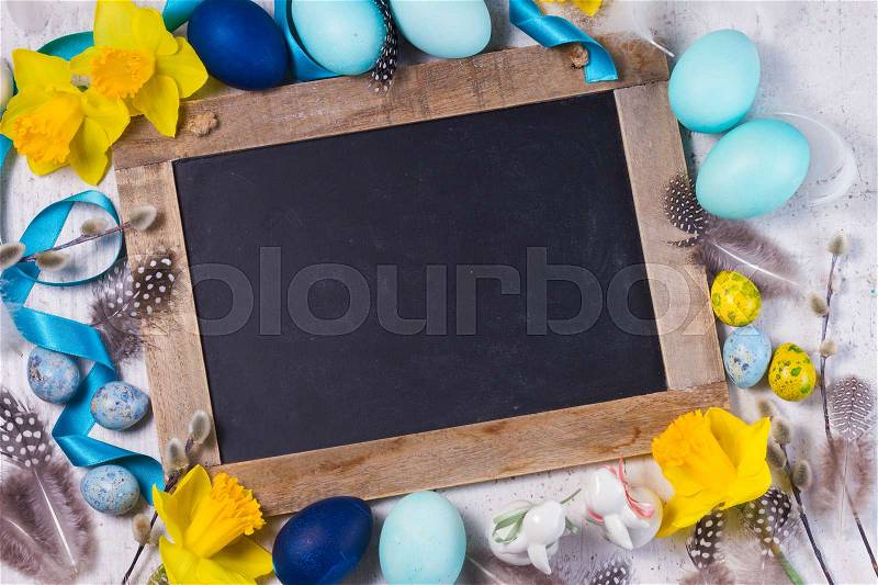 Easter frame with painted blue eggs and flowers and empty blackboard with copy space, stock photo