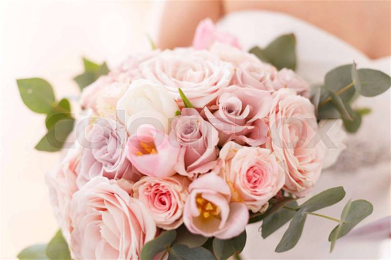 Brides bouquet of roses, tulips and eucalyptus, in her hands, stock photo
