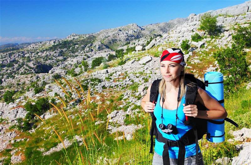 Traveling girl with backpack hiking in the mountains, eco tourism, stock photo