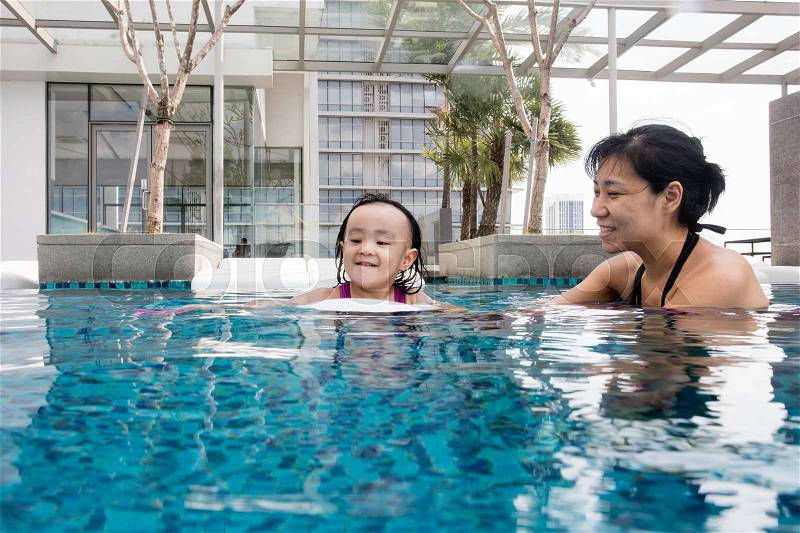 Asian Chinese mother and daugther playing at outdoor swimming pool on sunny day, stock photo