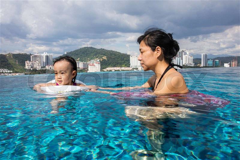 Asian Chinese mother and daugther playing at outdoor swimming pool on sunny day, stock photo