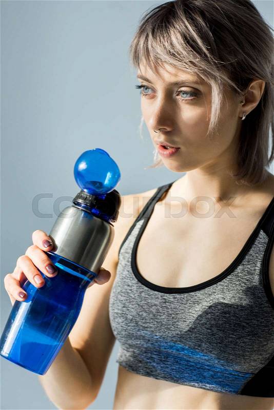 Portrait of sporty woman drinking water from bottle after training, stock photo
