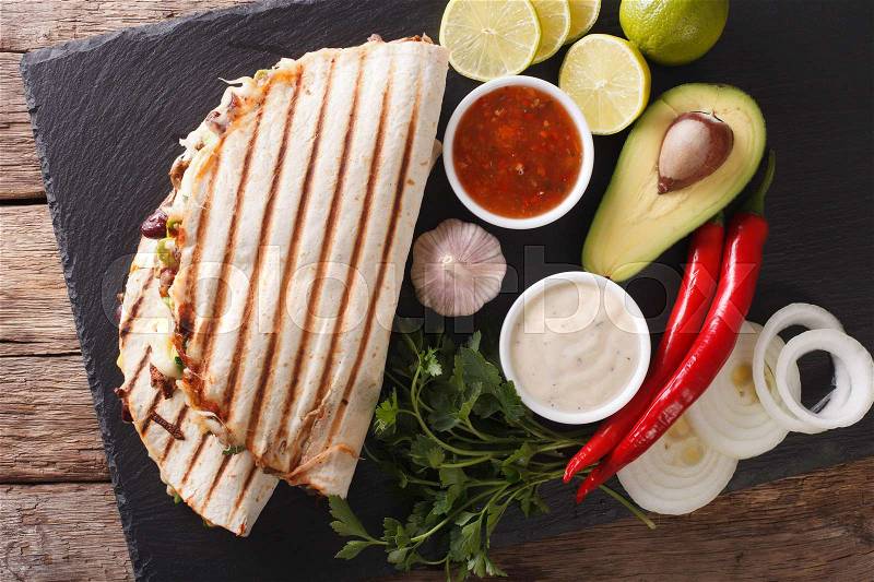 Mexican quesadilla with beef, beans, avocado and cheese close-up on the table. Horizontal view from above , stock photo