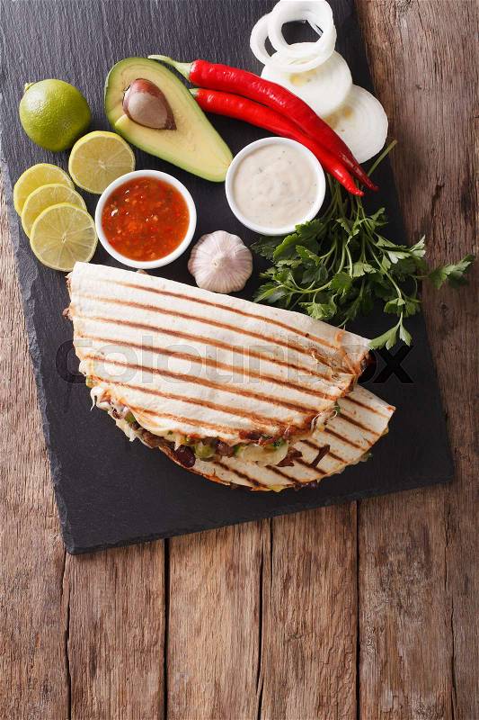 Mexican quesadilla with beef, beans, avocado and cheese close-up on the table. vertical view from above , stock photo
