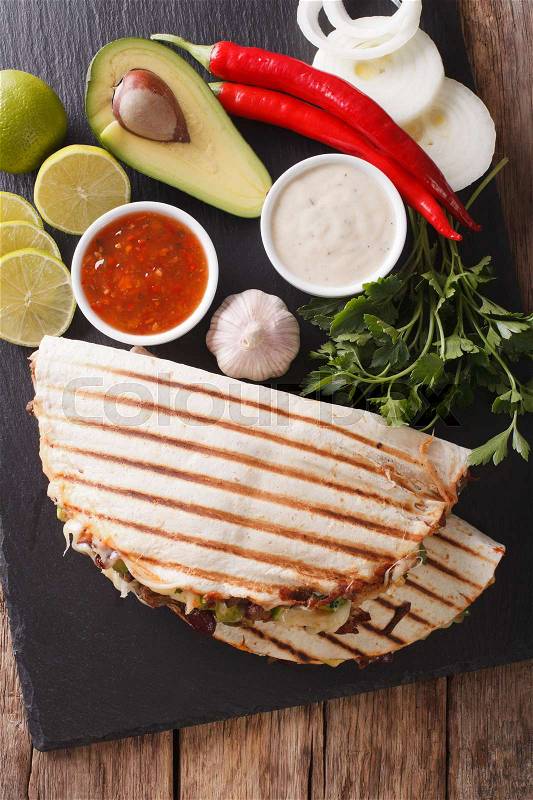 Quesadilla with minced beef, beans, avocado and cheese close-up on the table. vertical view from above , stock photo