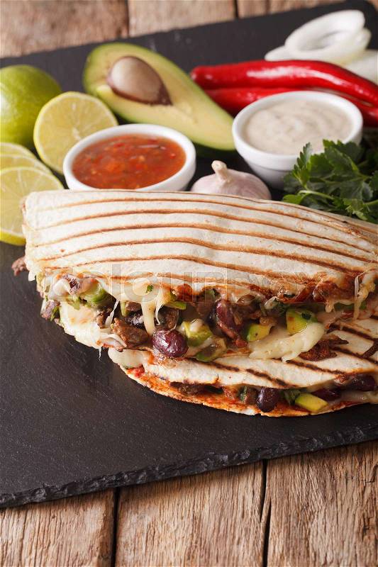 Quesadilla with beef, beans, avocado and cheese close-up on the table. vertical , stock photo