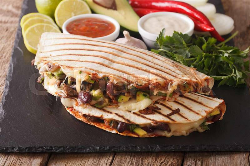 Mexican quesadilla with beef, beans, avocado and cheese close-up on the table. horizontal , stock photo