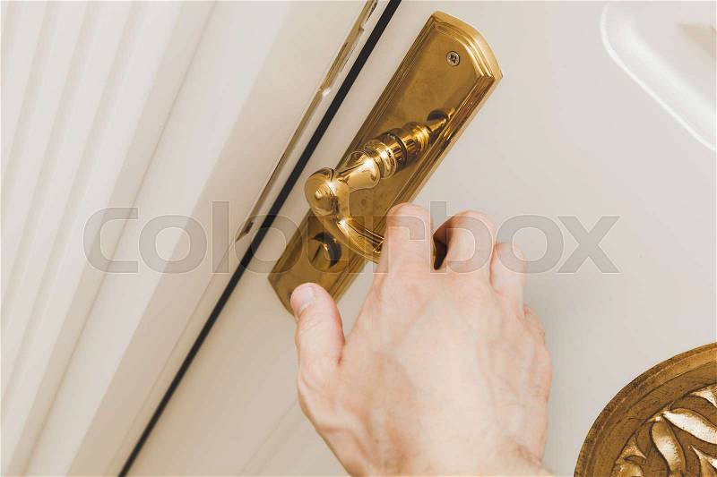 Male hand opens white wooden door with golden handle, close up photo with selective focus, stock photo