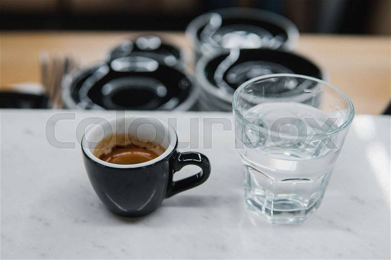 Cup with coffee near a glass of water on the table, stock photo