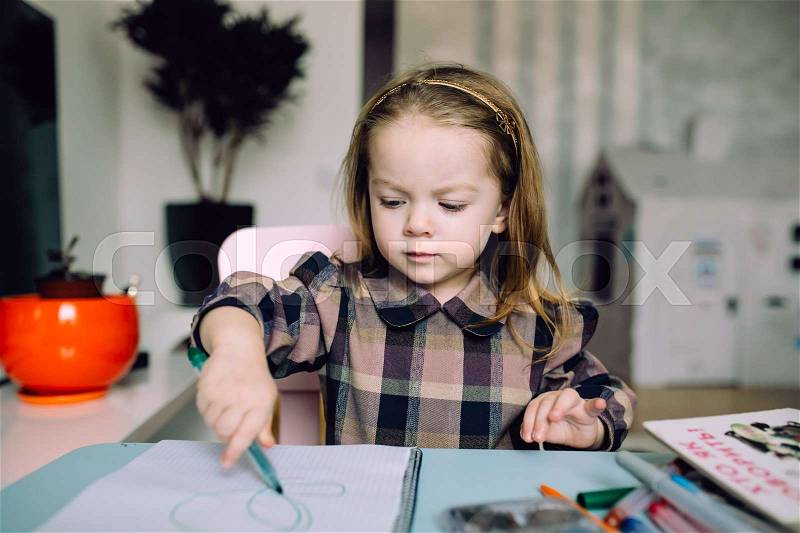 Happy little girl drawing with pencils at home, stock photo