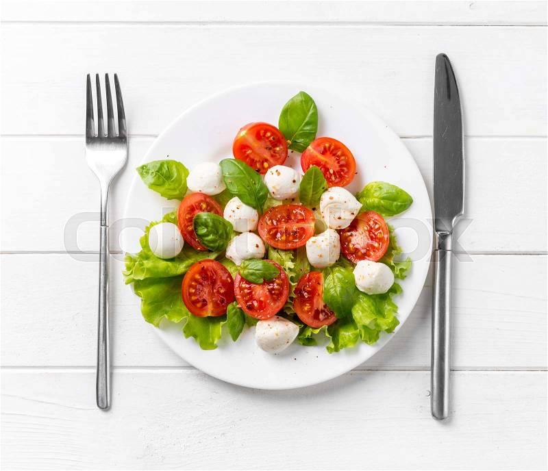 Round plate of fitness healthy salad with plenty of greens, tomatoes and cheese, topview, stock photo