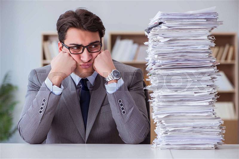 Businessman busy with paperwork in office, stock photo