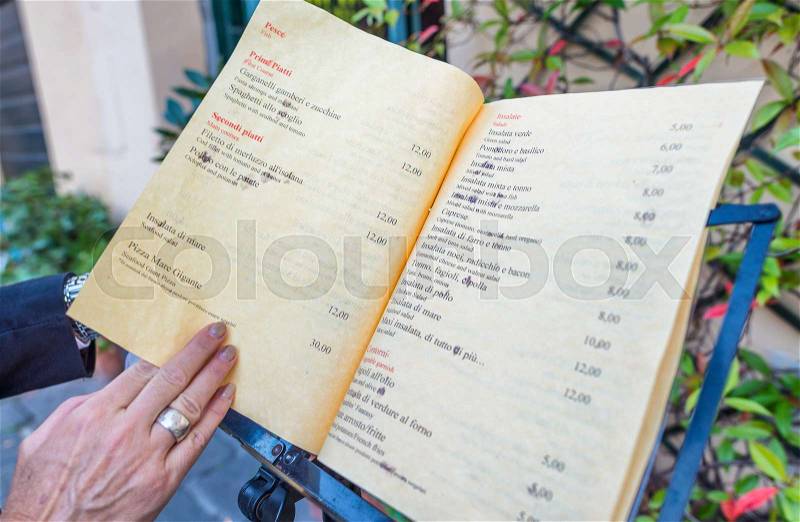 Woman hand touching italian restaurant menu, stock photo