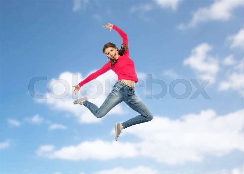 Happiness, freedom, motion and people concept - happy young woman jumping or dancing in air over blue sky background, stock photo